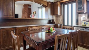 A modern kitchen with wooden cabinetry, a glass-top dining table, and a fruit bowl.