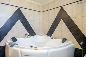 A bathroom with a freestanding bathtub, a towel, and a showerhead. - Eleni's Villa (Kissamos)