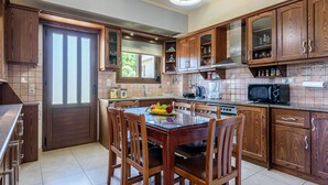 A modern kitchen with wooden cabinets, a dining table with chairs, and a fruit bowl.