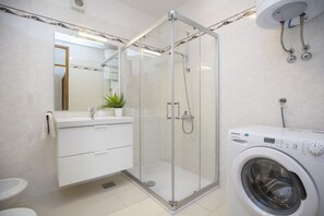 Chuveiro, toalhas de banho, shampoo, papel higiênico