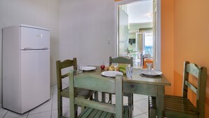 Ein Essbereich mit einem Tisch für zwei Personen, einem Kühlschrank und Blick in einen weiteren Raum.