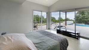 A bedroom with a large bed, a sliding glass door leading to an outdoor area with a pool and lounge chairs. - Villa 'Gecko' with Sea View, Wi-Fi and Air Conditioning (SARI SOLENZARA)