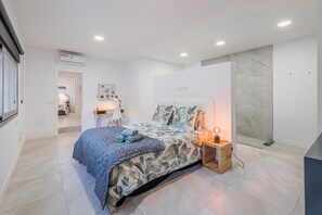 Ein modernes Schlafzimmer mit Bett, Nachttisch und einer Duschkabine.