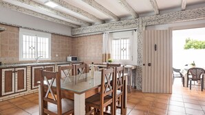 Una cocina con una mesa de comedor, sillas, un microondas y vistas al exterior.