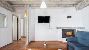 Una sala de estar con chimenea, televisor y sofá.