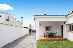 A patio with a grill, a table with chairs, and a small garden area. - Chalet Casa Playamar near the beach with garden, pool and Wi-Fi (Vejer de la Frontera)