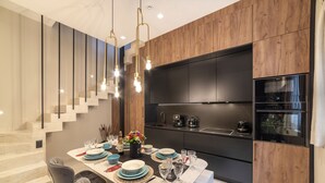 A modern kitchen with dark cabinetry, a built-in oven, and a dining area with a marble table set for six. - Located in the Heart of Heraklion, combining Elegance & Modern Luxury.  (Iraklio)