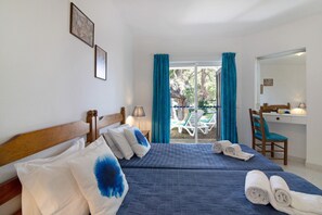 A hotel room with two beds, a desk, a chair, and a view of the outside.