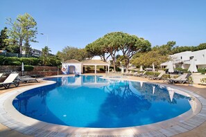 A circular swimming pool with lounge chairs and a gazebo.