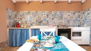 Una cocina con salpicadero de azulejos, una mesa de comedor con mantel azul y un horno blanco.