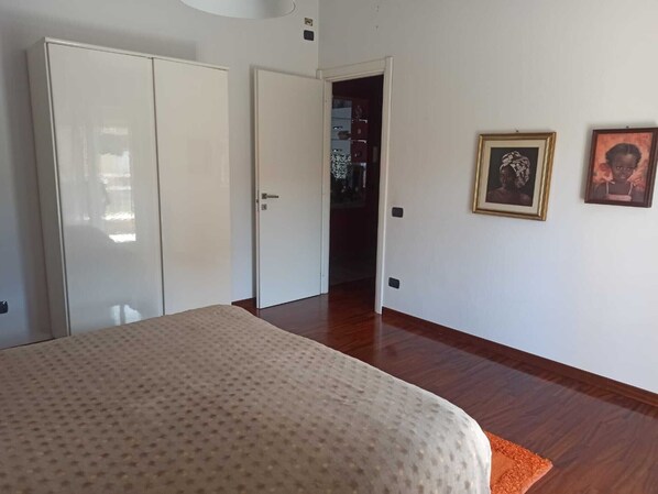 A bedroom with a bed, a wardrobe, and a door leading to another room.