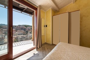 A bedroom with a large window, a bed, and a wardrobe.