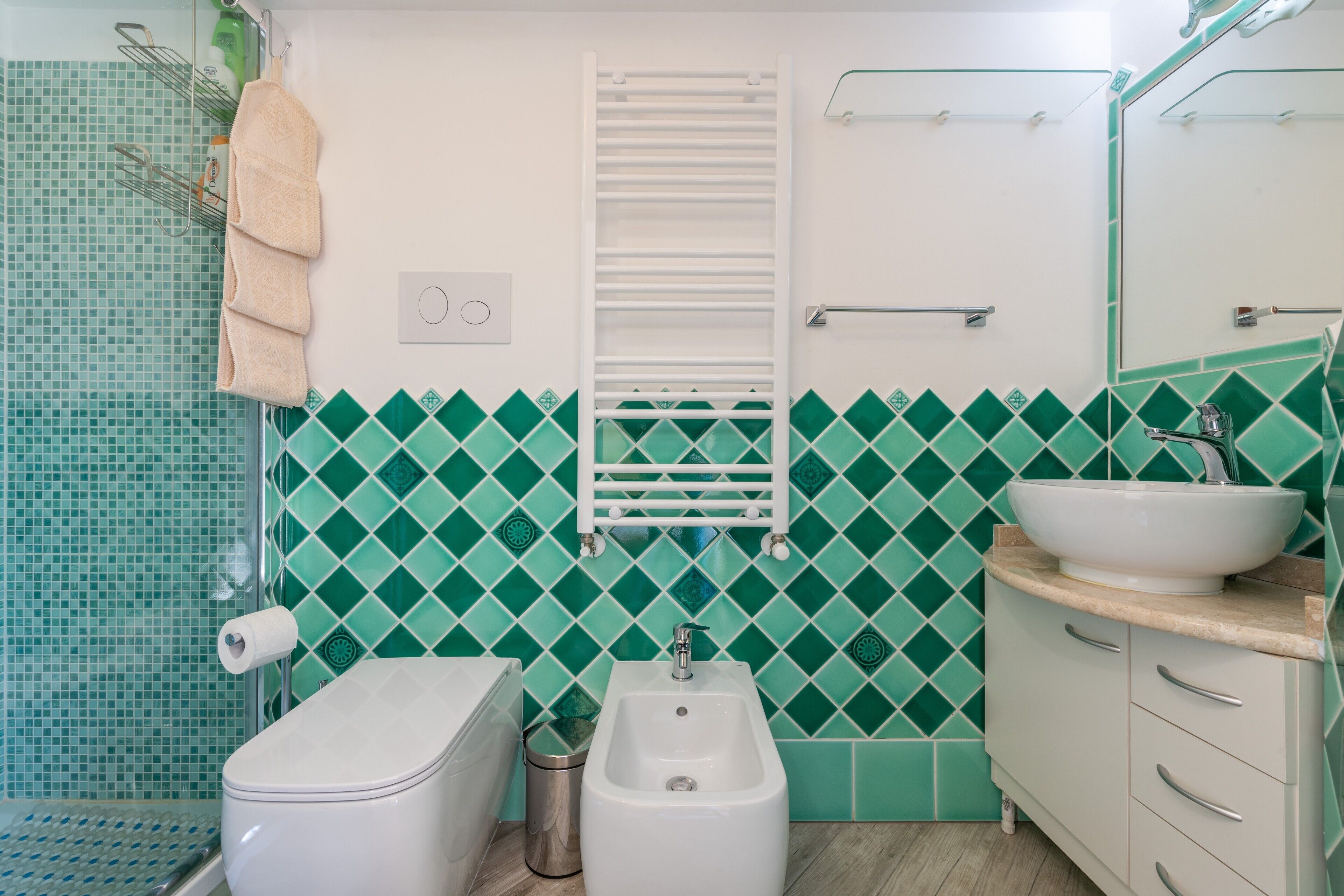 Ein Badezimmer mit Toilette, Bidet, Waschbecken, Handtuchhalter und Spiegel.