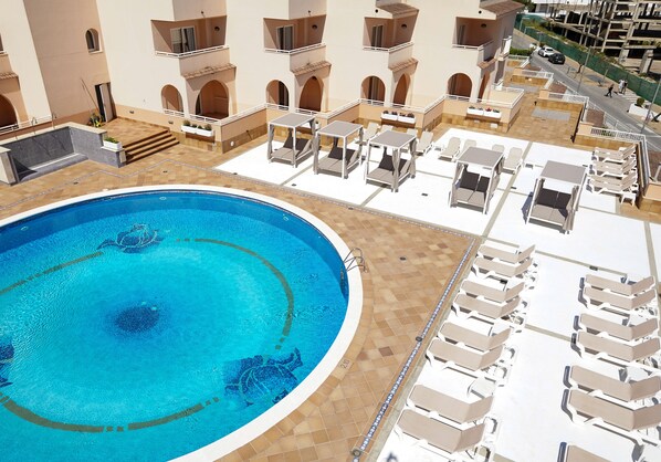 A swimming pool with sun loungers and a tiled deck area. - Rosamar Ibiza Hotel (Sant Josep de sa Talaia)