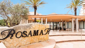 A hotel entrance with a large rock sign reading "ROSAMAR" and palm trees in the background. - Rosamar Ibiza Hotel (Sant Josep de sa Talaia)