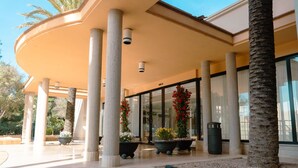 A modern building with a curved roof, large columns, and potted plants. - Rosamar Ibiza Hotel (Sant Josep de sa Talaia)