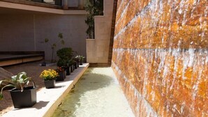 A narrow water feature with plants on the left and a textured wall on the right. - Rosamar Ibiza Hotel (Sant Josep de sa Talaia)