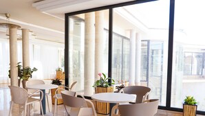 A spacious indoor area with large windows, modern furniture, and potted plants. - Rosamar Ibiza Hotel (Sant Josep de sa Talaia)