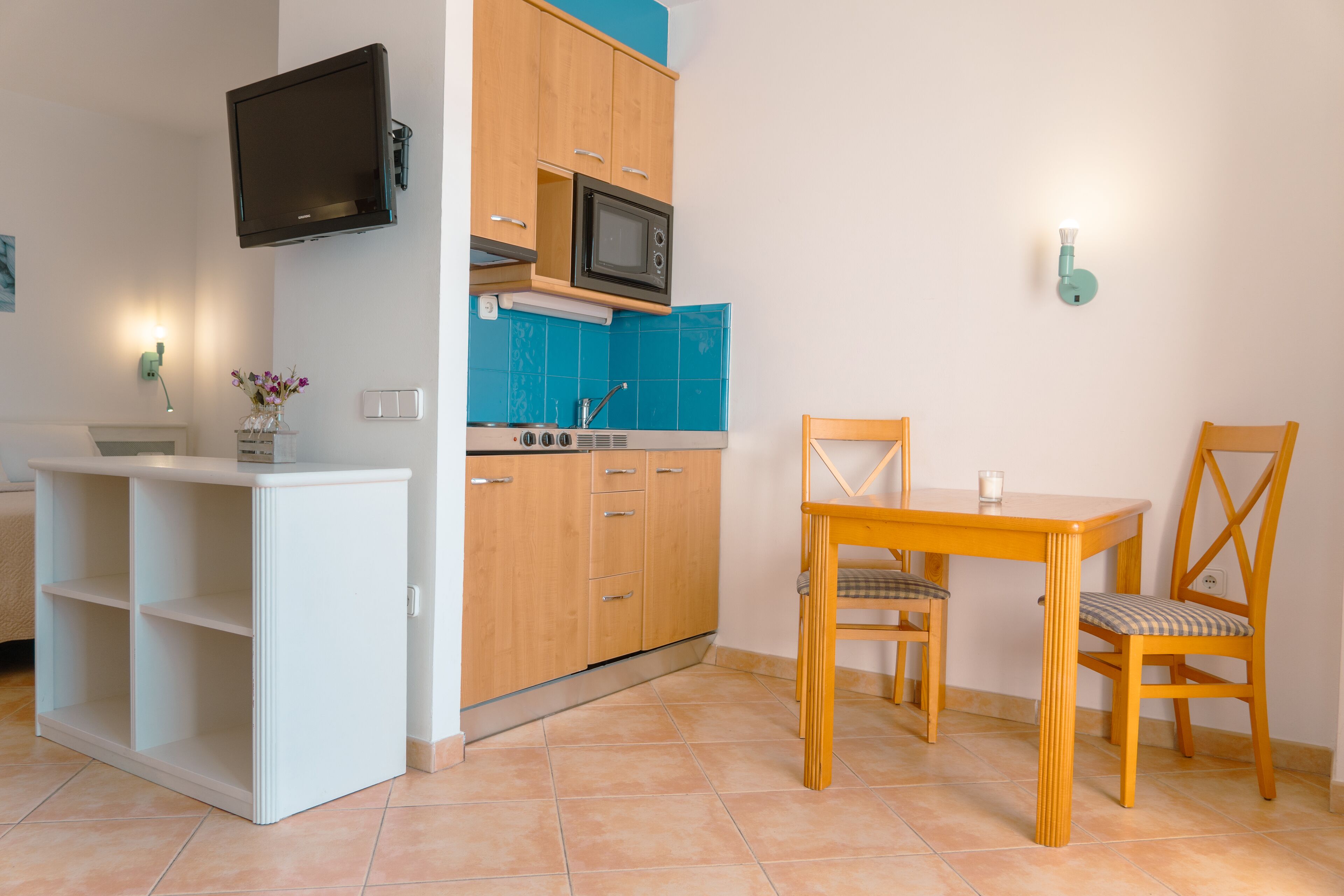 A compact kitchen with a microwave, a small dining table, and a chair.