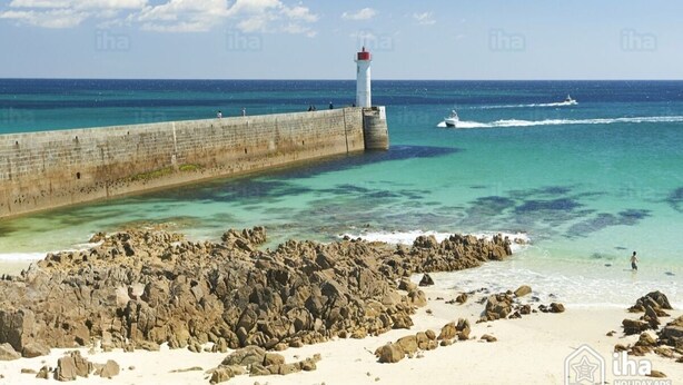 A coastal scene with a lighthouse, clear turquoise waters, and a rocky shoreline.