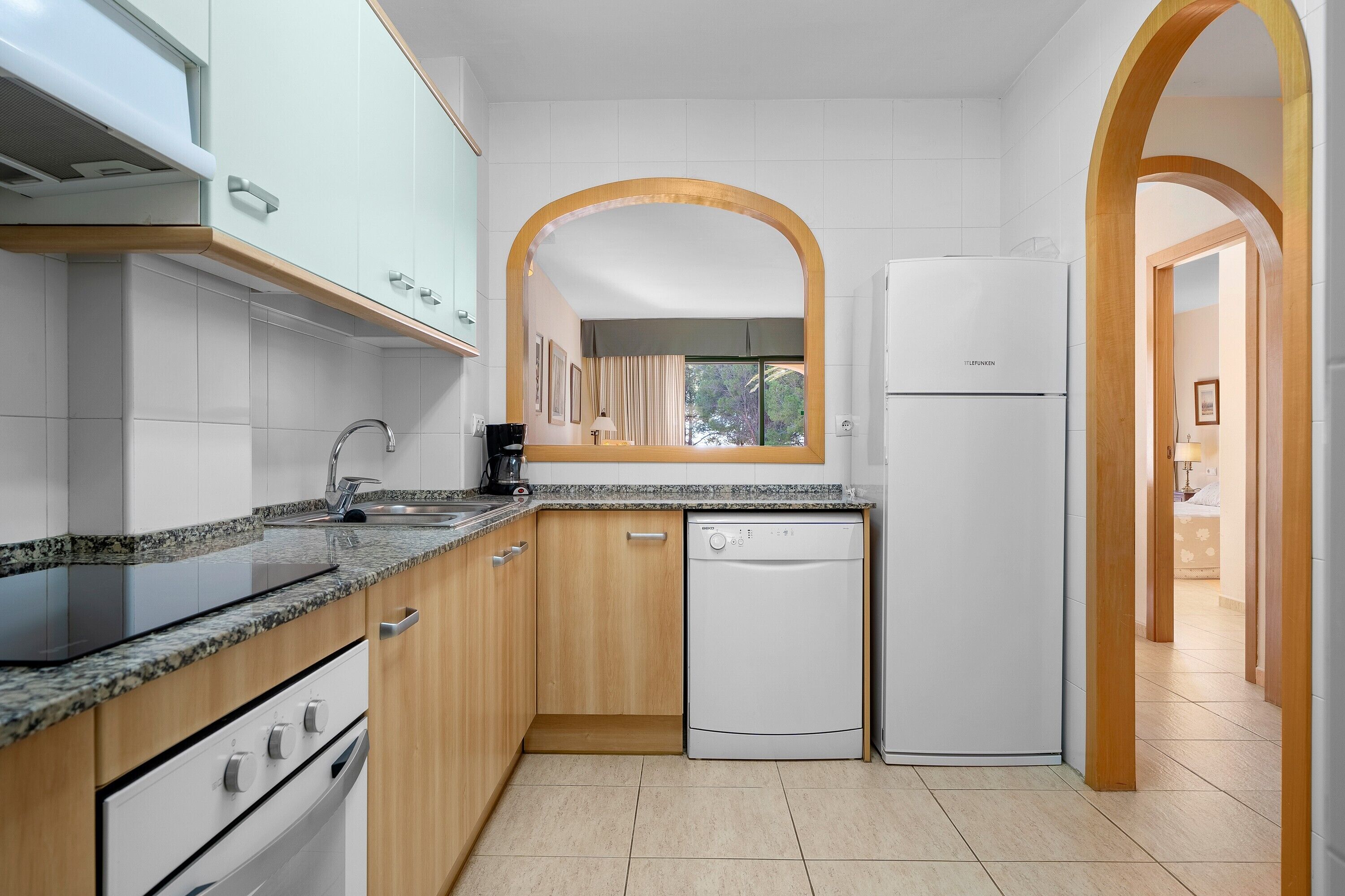 Una cocina moderna con armarios blancos, lavavajillas y refrigerador.