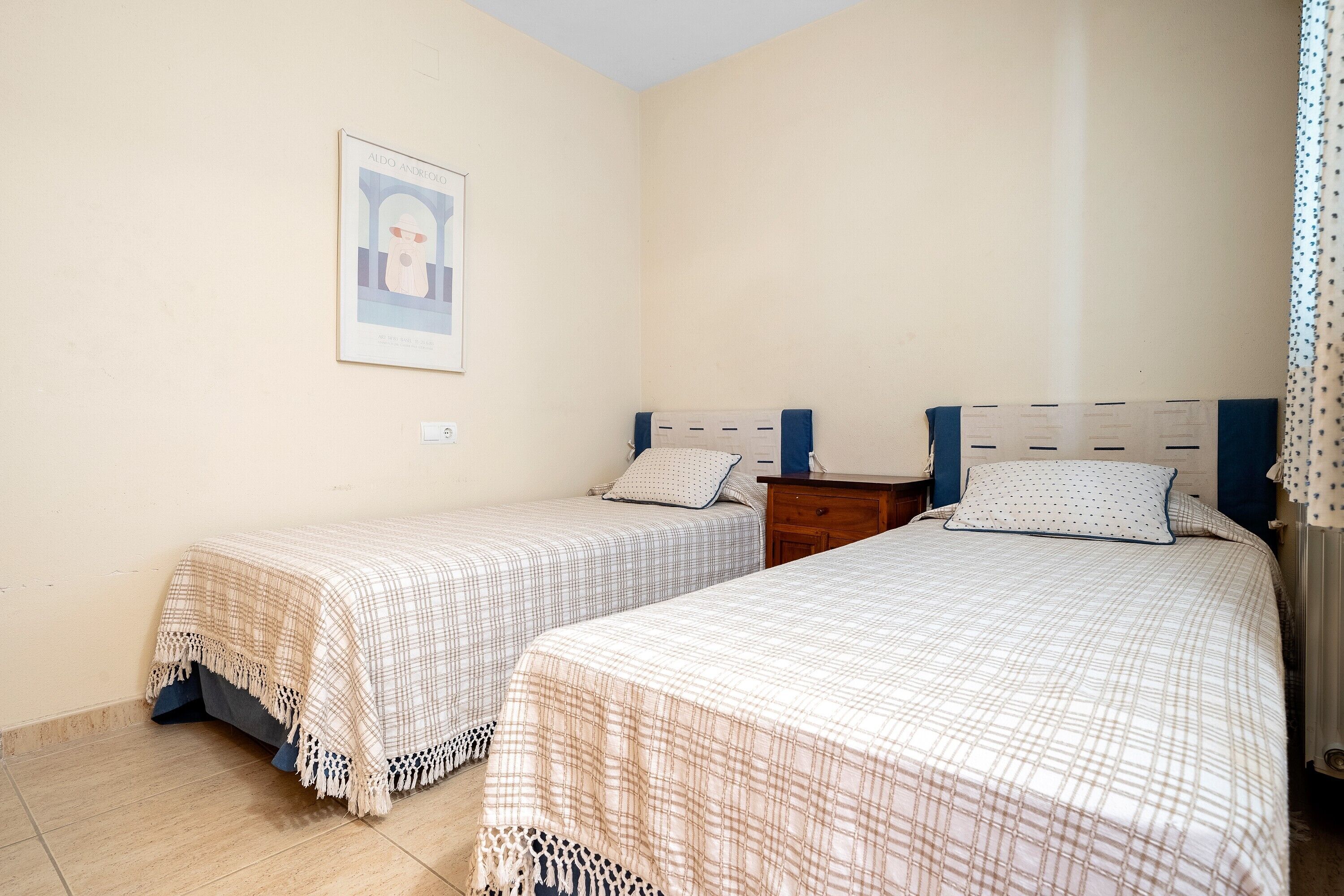 Un dormitorio con dos camas, una mesita de noche, un aparador y un cuadro en la pared.