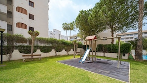 A playground with a slide, benches, and a fenced area. - Fin Albir Spaniahome Holiday Apartment with Pool, Furnished Terrace & Wi-Fi (l'Alfàs del Pi)