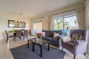 A living room with a sofa, armchair, dining table, and chairs.