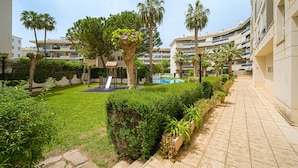 A courtyard with a swimming pool, palm trees, and a playground. - Fin Albir Spaniahome Holiday Apartment with Pool, Furnished Terrace & Wi-Fi (l'Alfàs del Pi)
