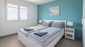 A bedroom with two beds, a nightstand, a lamp, and a painting on the wall. - 'Apartment ARCE Frontline Seaview' with Pool, Balcony & Wi-Fi (Nerja)
