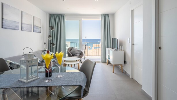 A modern room with a dining table, chairs, a TV, and a balcony with a view of the sea. - 'Apartment ARCE Frontline Seaview' with Pool, Balcony & Wi-Fi (Nerja)