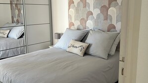 A bedroom with a bed, a wardrobe, and a patterned headboard.