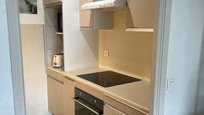 A compact kitchen with a built-in oven, a stovetop, and a microwave.
