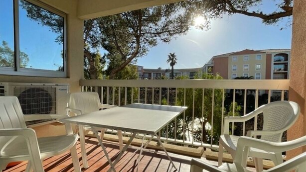 A balcony with a table and chairs, overlooking a body of water and buildings.