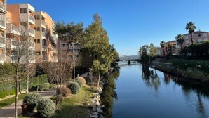 A riverside view with modern apartment buildings, a bridge, and well-maintained greenery.