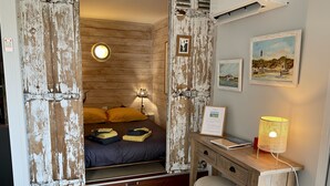 Ein rustikales Zimmer mit einem Bett, einem Schreibtisch und einer Wand-Klimaanlage.