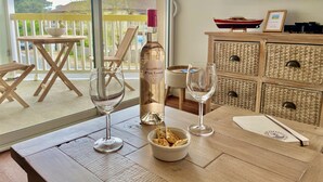 Ein Holztisch mit einer Weinflasche, zwei Weingläsern und einer Schüssel mit Snacks.