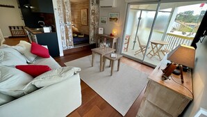 Ein modernes Wohnzimmer mit einer Couch, einem kleinen Tisch und Blick auf den Balkon.