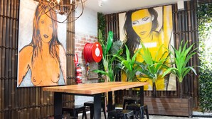 Un comedor con una mesa de madera, sillas negras y dos cuadros grandes en las paredes.