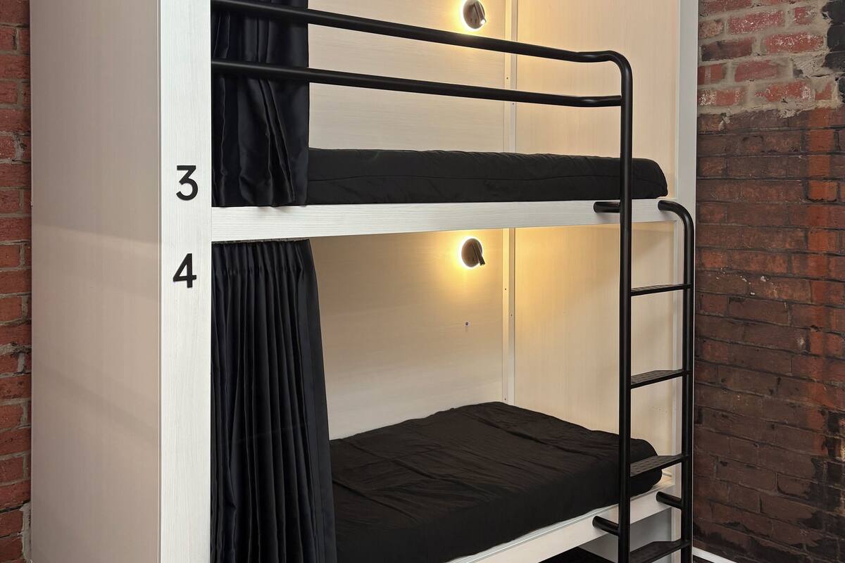A bunk bed with numbers 3 and 4, a black curtain, and a wall with a brick pattern.
