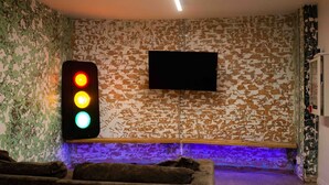 Una habitación con semáforo, televisor montado, banca y sofá.