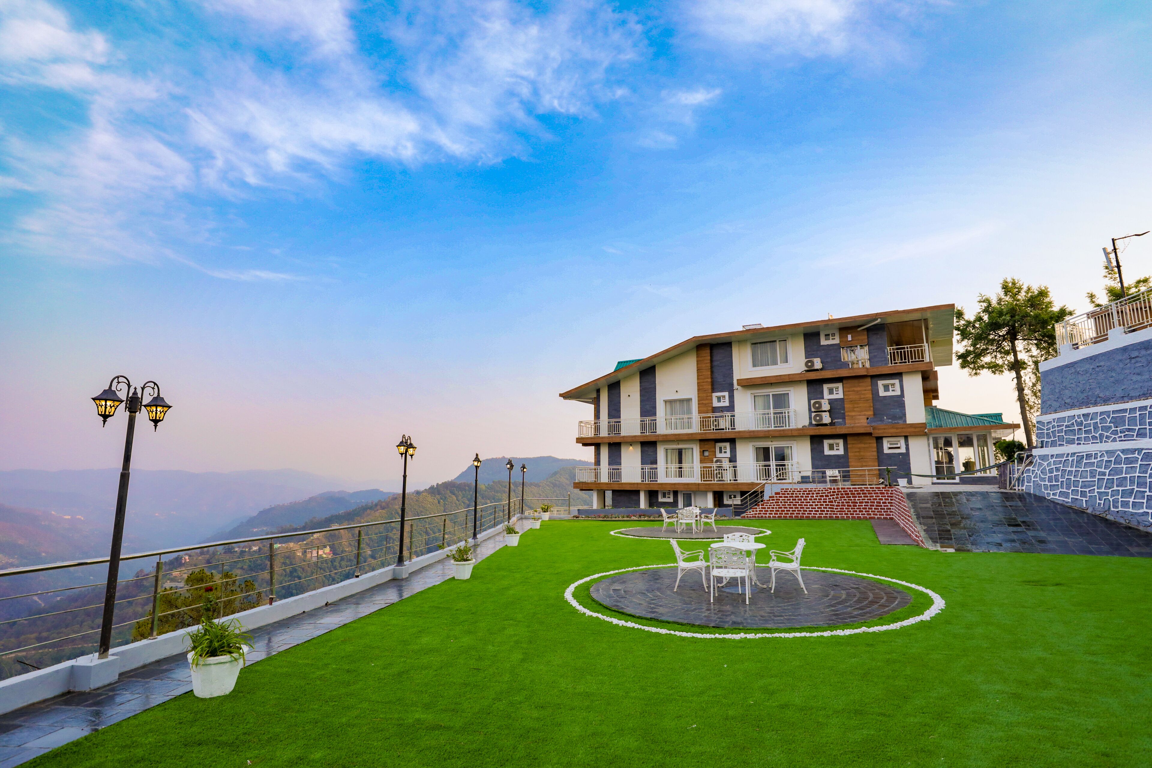 Ein Hotel mit Dachgarten, Sitzgelegenheiten im Freien und Blick auf die Berge.
