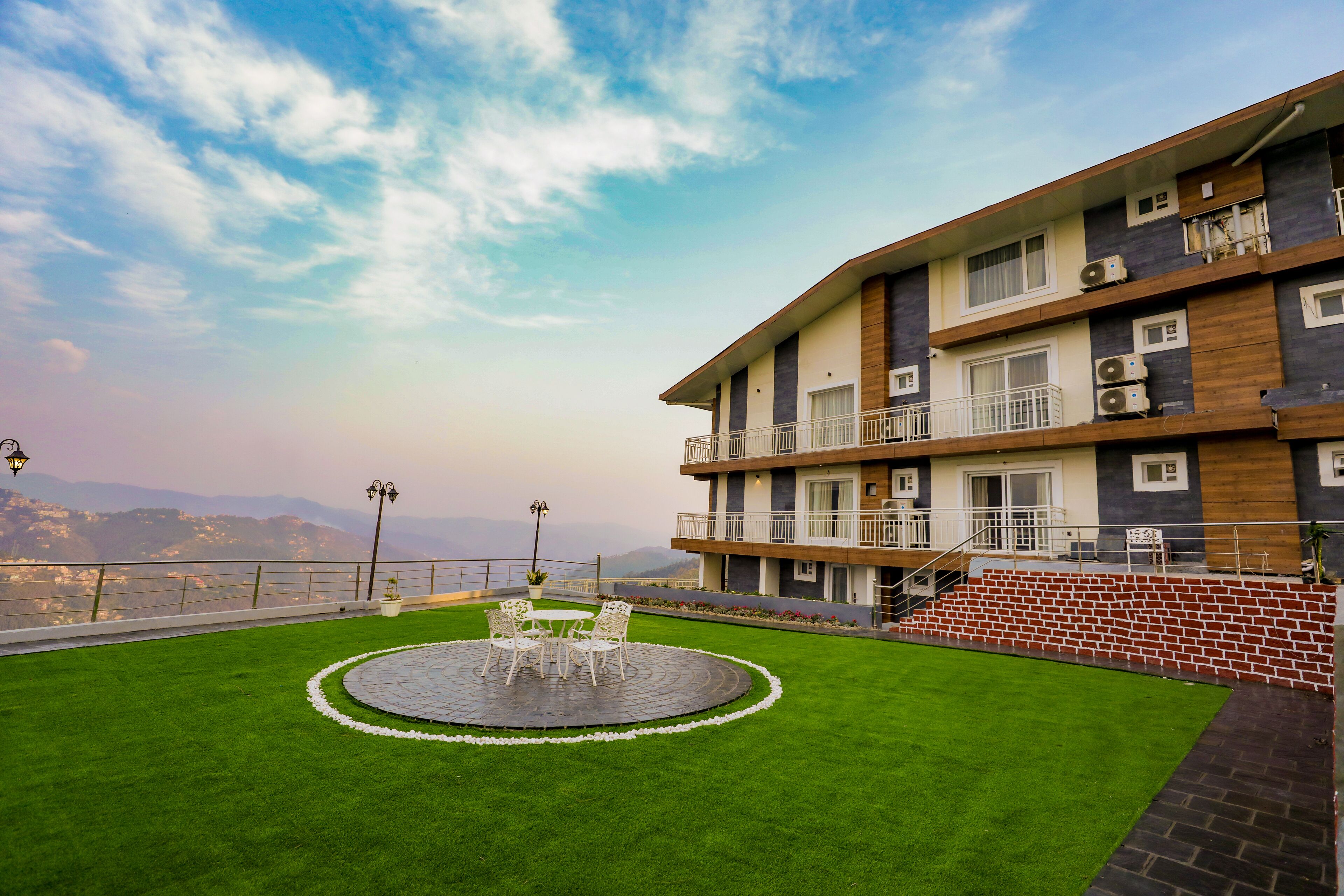 Un hotel con jardín en la azotea, mobiliario exterior y vistas a la montaña.