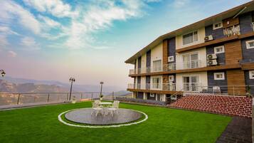 Un hotel con jardín en la azotea, mobiliario exterior y vistas a la montaña.