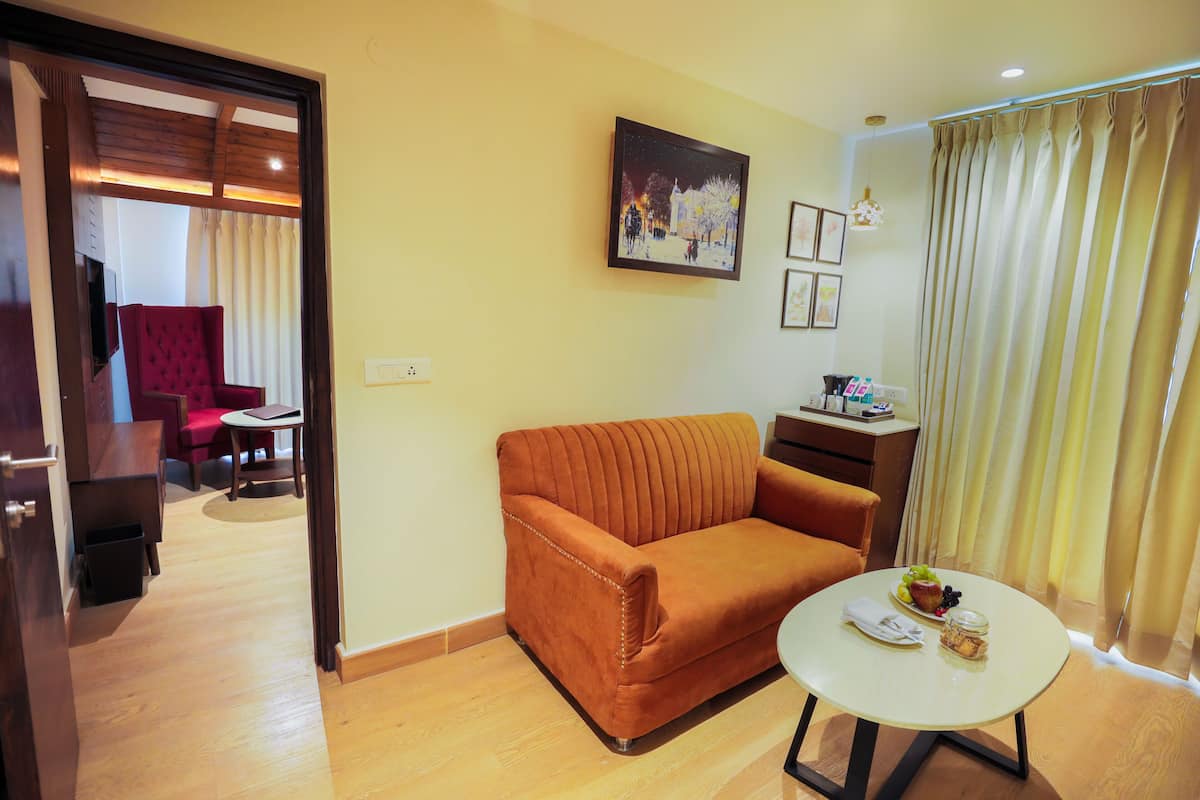 A living room with a sofa, a small table with a tray of food, and a painting on the wall.