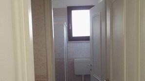 Een badkamer met toilet, douche en raam.