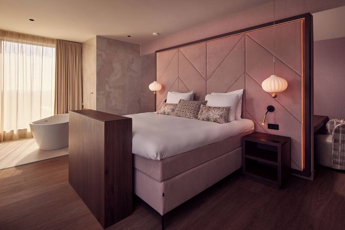 A modern bedroom with a large bed, bedside tables, a nightstand, and a built-in bench.