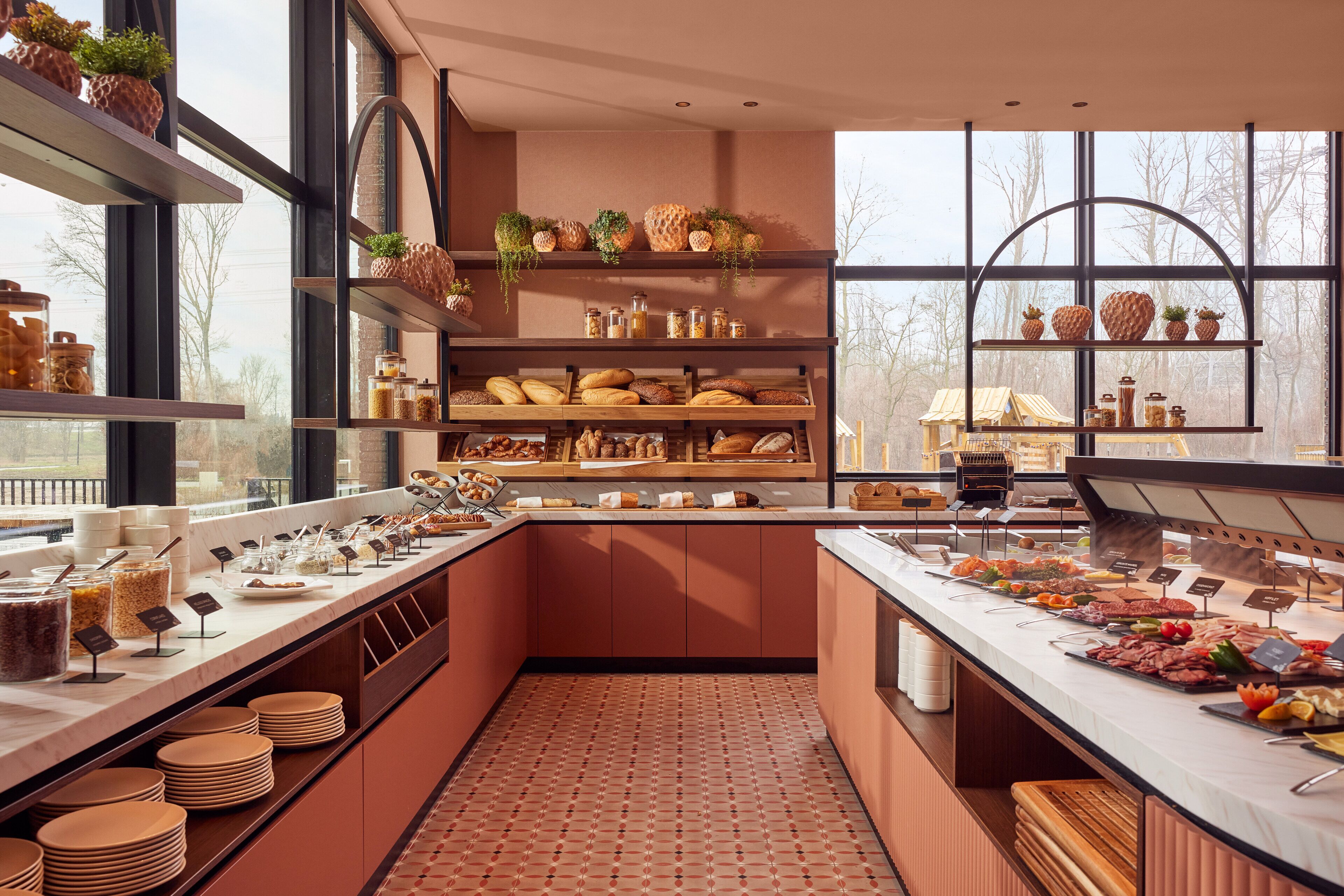 A buffet area with various food items and a view of trees outside.