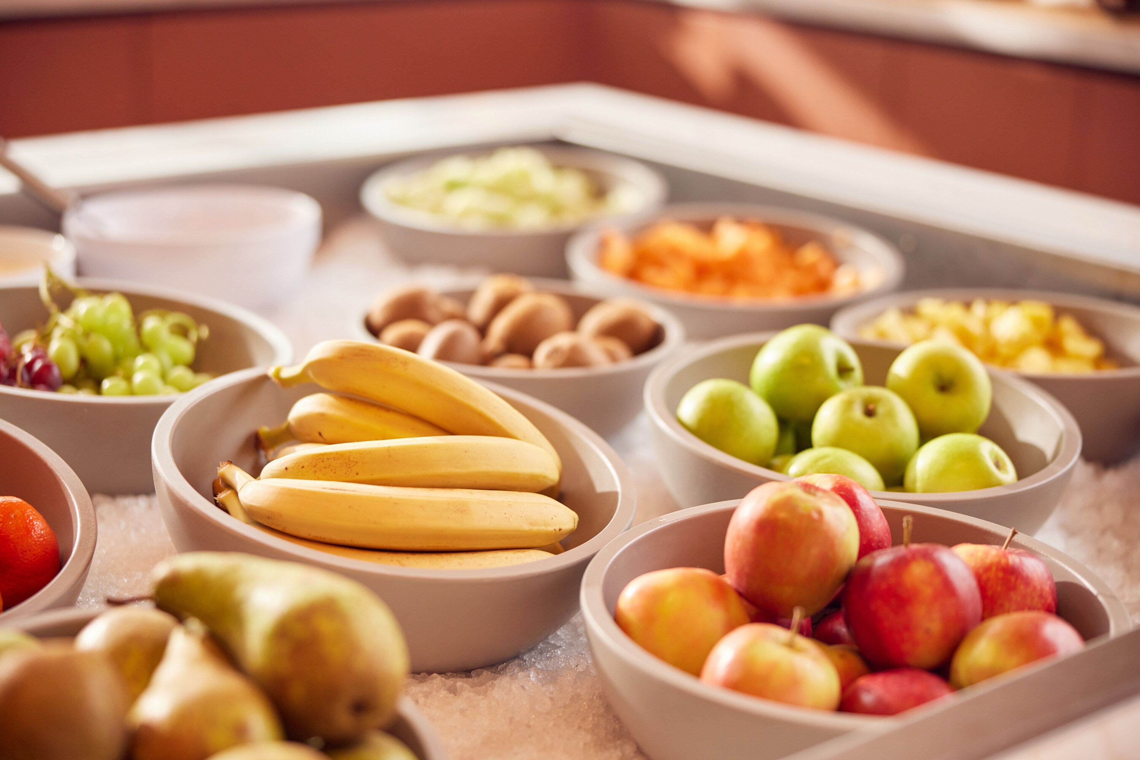 Ein reichhaltiges Buffet mit verschiedenen Früchten und Gemüsesorten, darunter Bananen, Äpfel und Trauben.