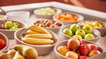 Un bufé con diversas frutas y verduras, como plátanos, manzanas y uvas.